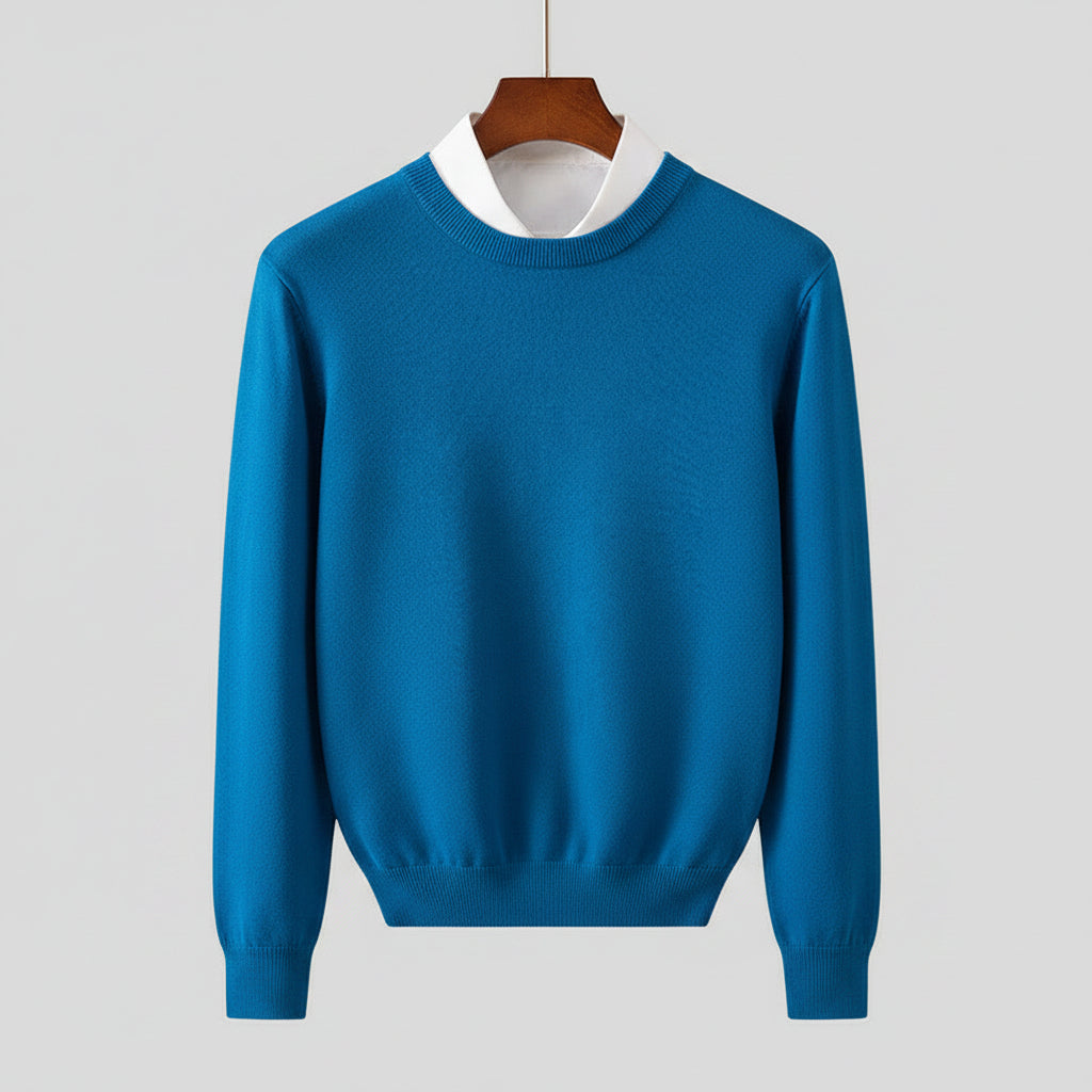 Blue sweater on a hanger against a dark background with wooden furniture.