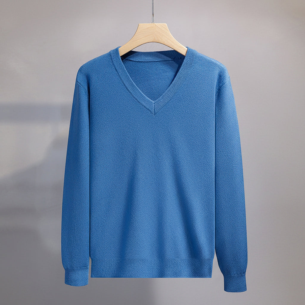 Blue sweater on a hanger against a gray background