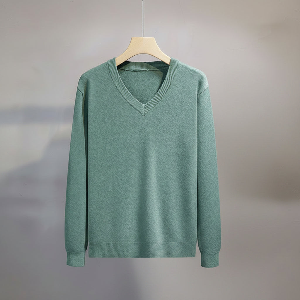 Green sweater on a hanger against a gray background
