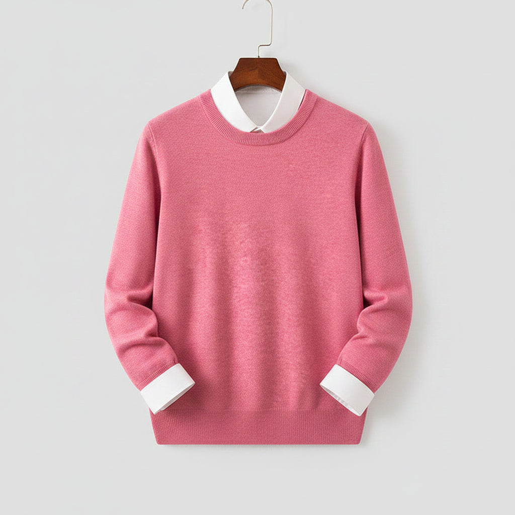 Pink sweater on a hanger against a dark background with wooden furniture.