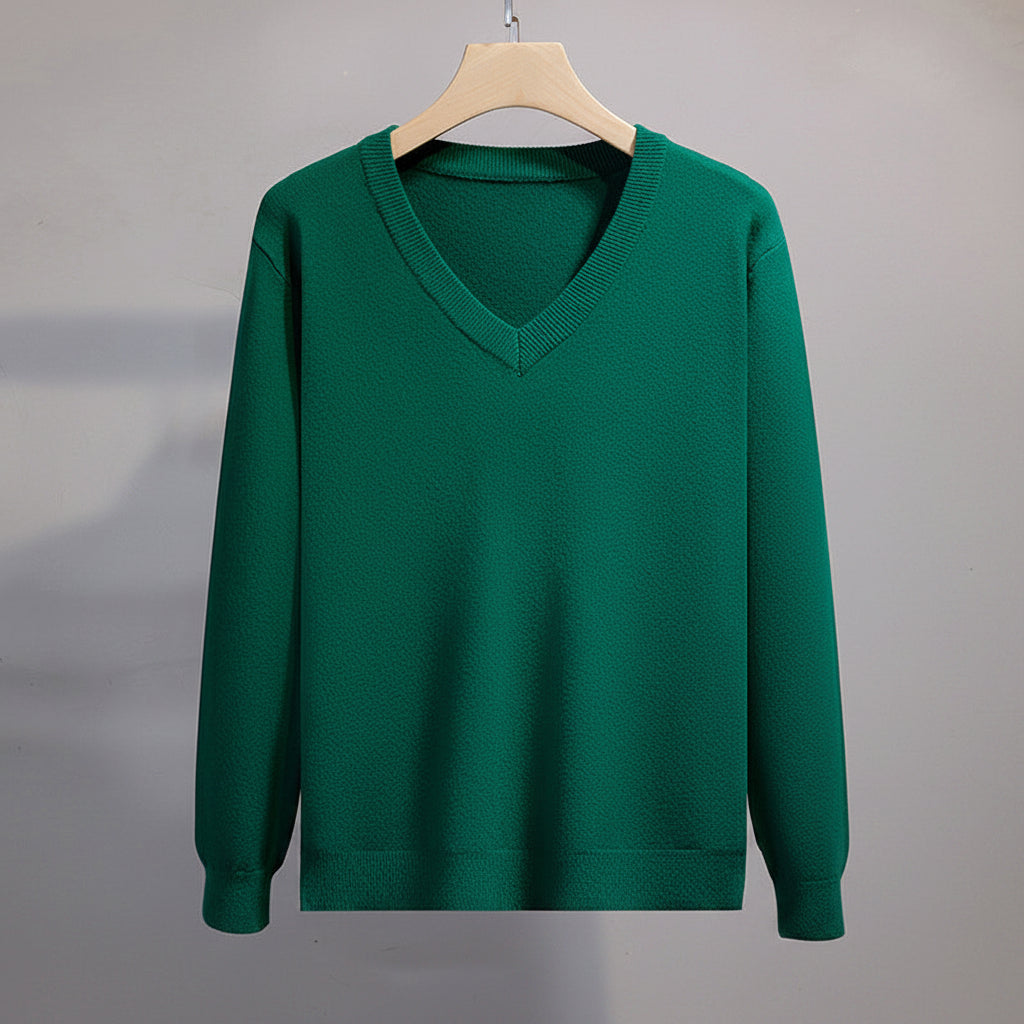 Green sweater on a hanger against a gray background