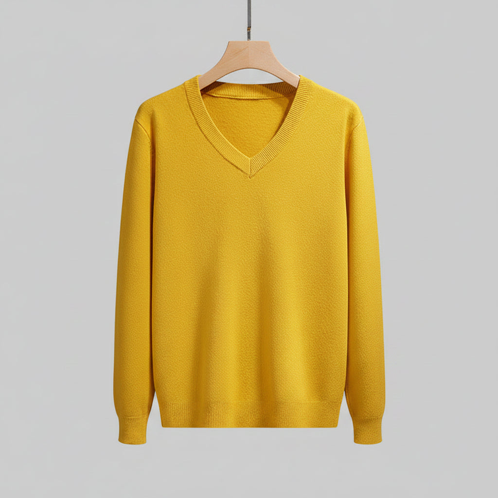 Yellow sweater on a hanger against a neutral background