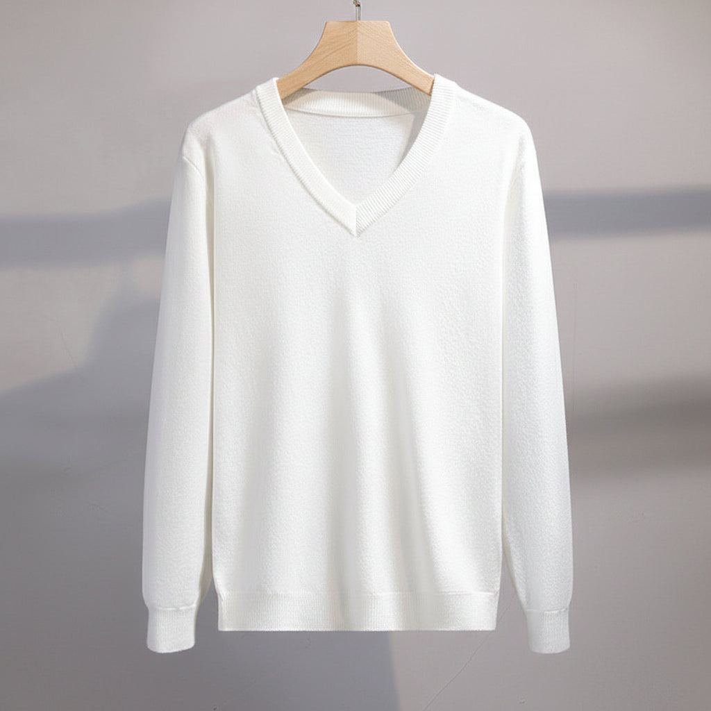 White sweater on a hanger with gray pants next to it against a neutral background