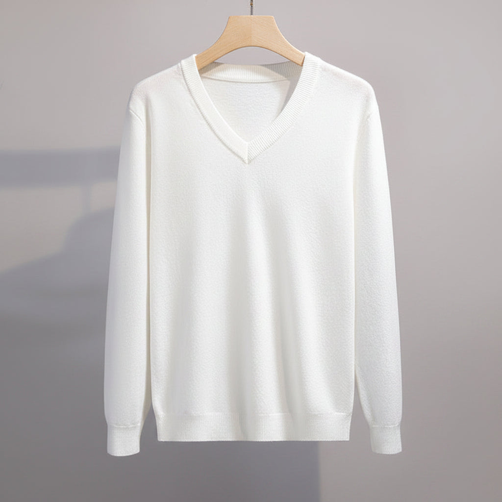 White sweater on a hanger with gray pants next to it against a neutral background
