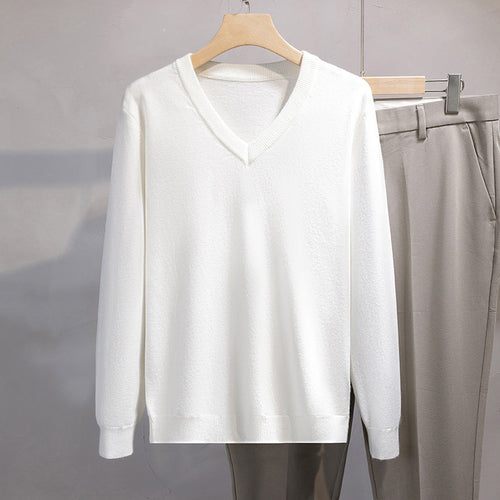 White sweater on a hanger with gray pants next to it against a neutral background