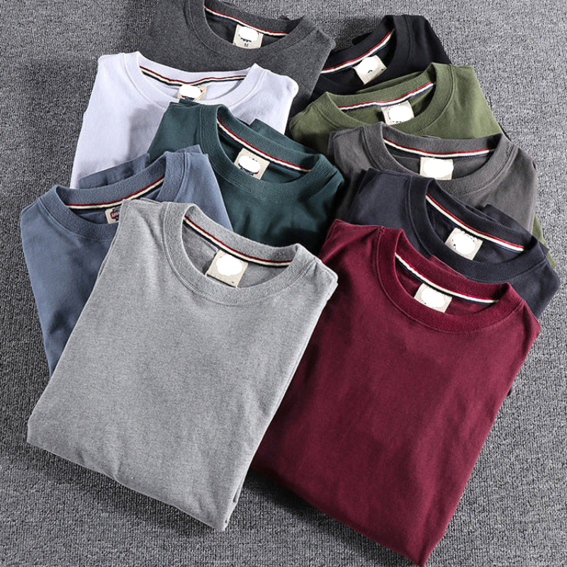 Folded t-shirts in various colors arranged on a gray surface