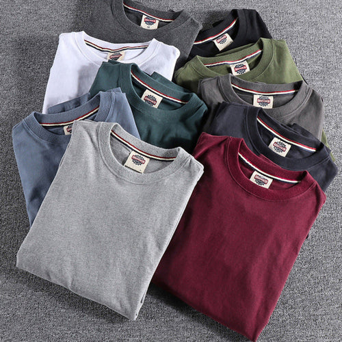 Folded t-shirts in various colors arranged on a gray surface