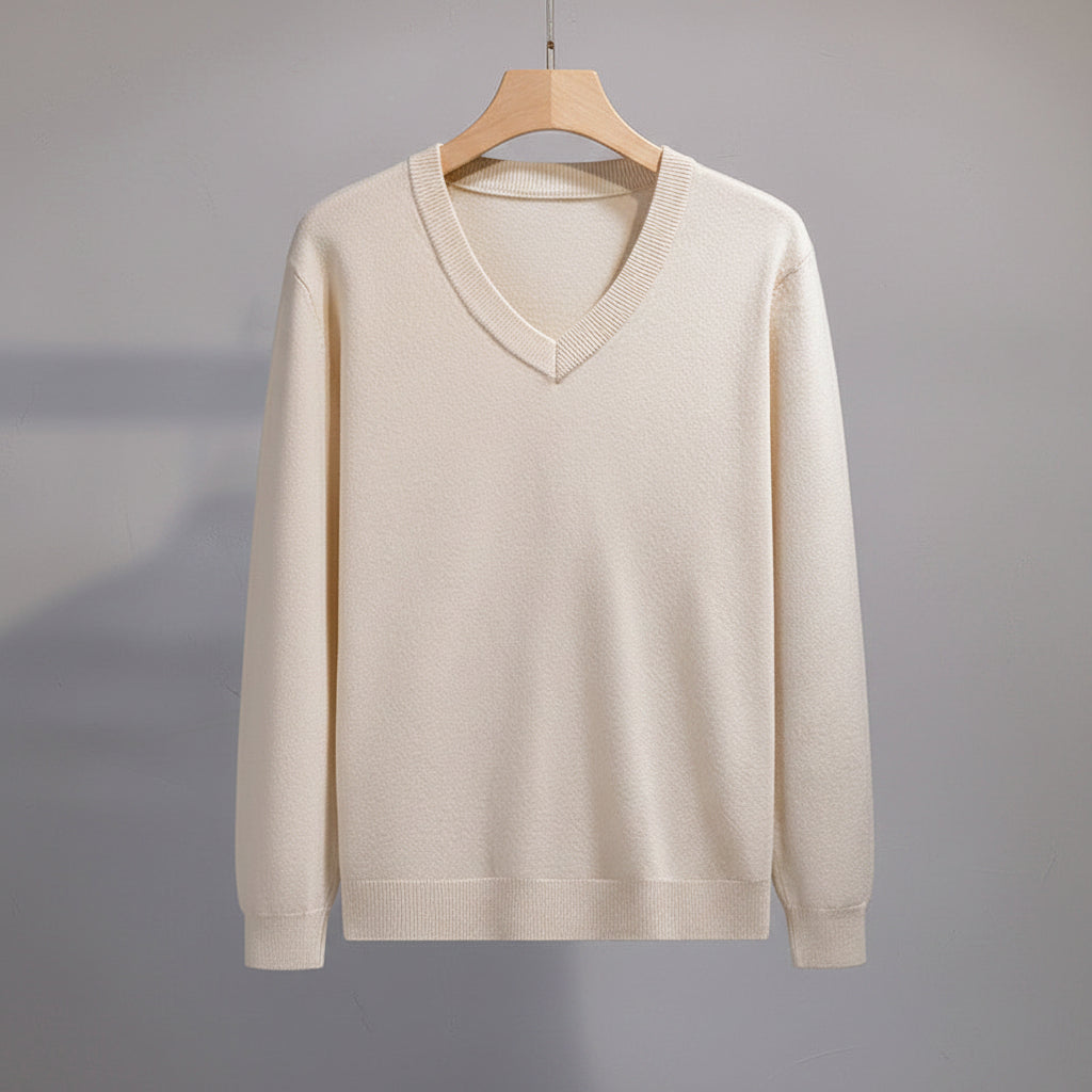 Beige sweater on a hanger with black pants in the background