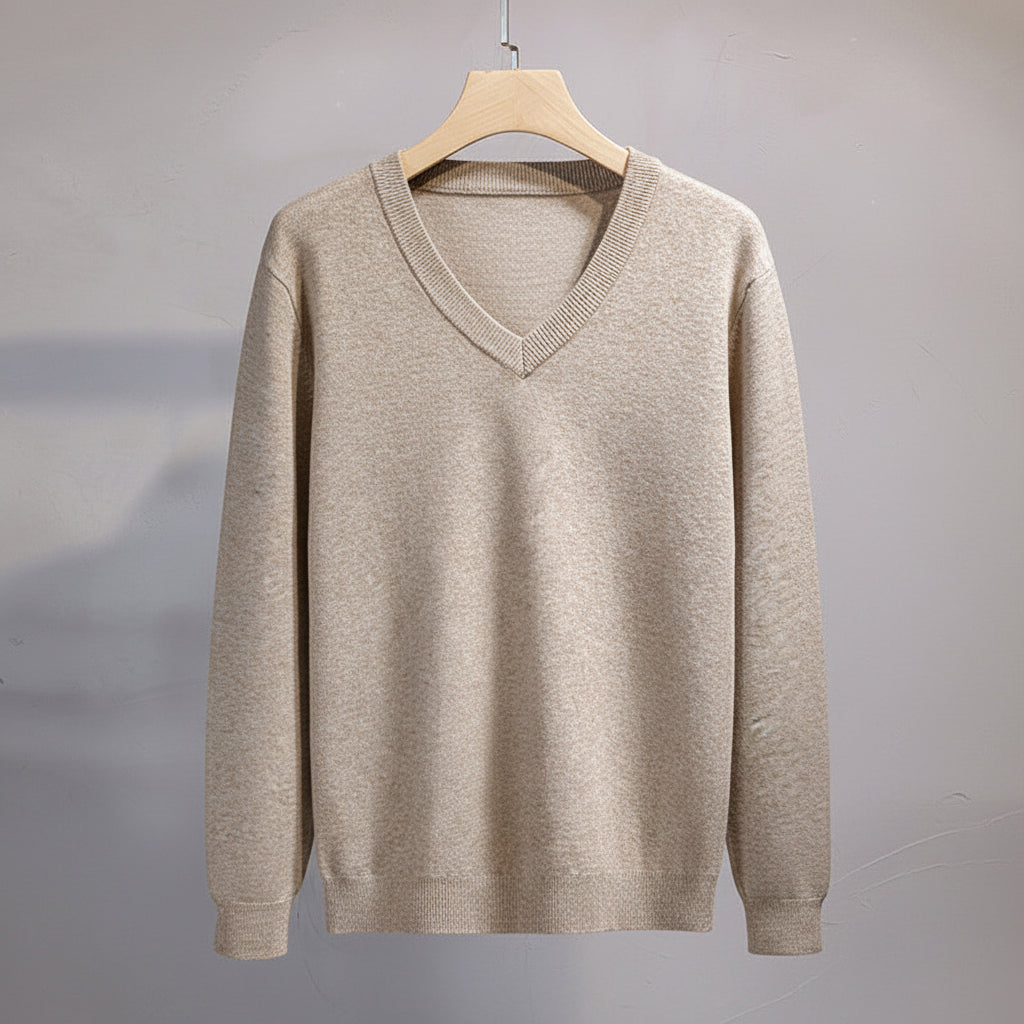 Beige sweater on a hanger against a gray background